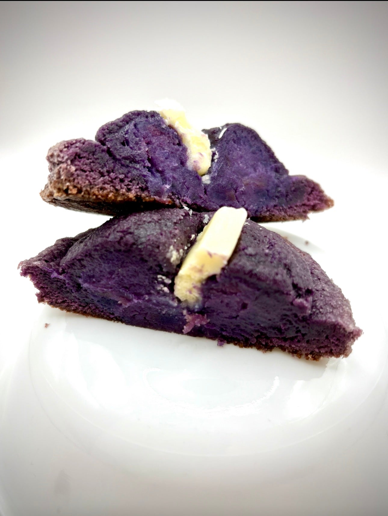 Two slices of purple cookie with white chocolate on a white background